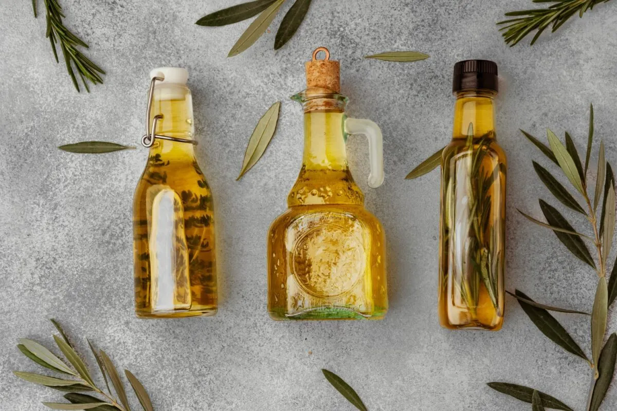 Was Sind Die Vorteile Von Olivenöl, Wie Kann Man Es Konsumieren? 1 Glasflasche-Mit-Olivem-Öl-Grauem-Hintergrund